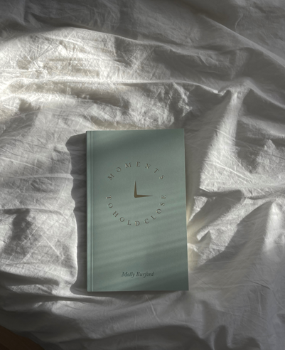 Moments To Hold Close Book Laying On Bed Sheets
